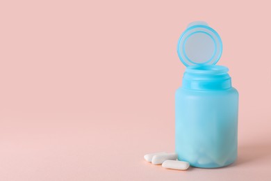 Photo of Jar with chewing gums on light pink background. Space for text