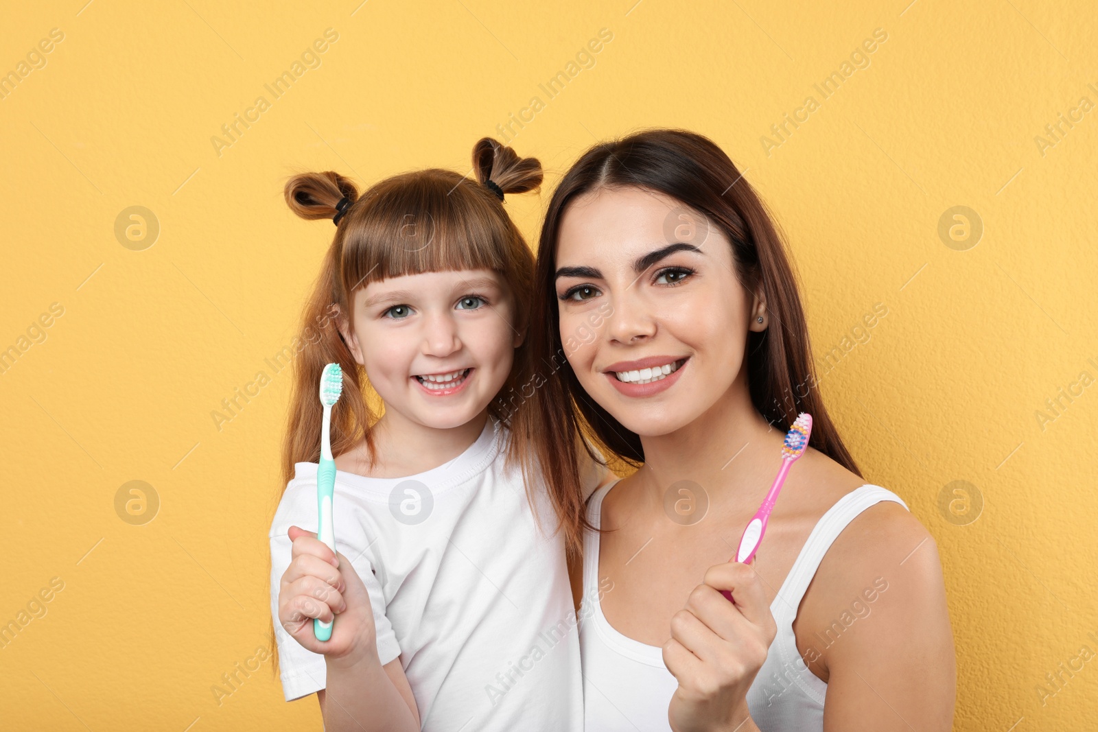 Photo of Little girl and her mother  with toothbrushes on color background. Teeth care