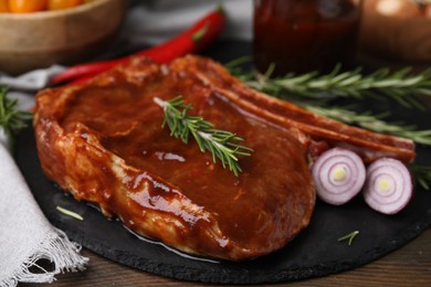 Photo of Tasty marinated meat, rosemary and onion on wooden table, closeup
