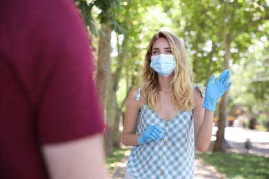 Photo of Woman in protective face mask saying hello outdoors. Keeping social distance during coronavirus pandemic