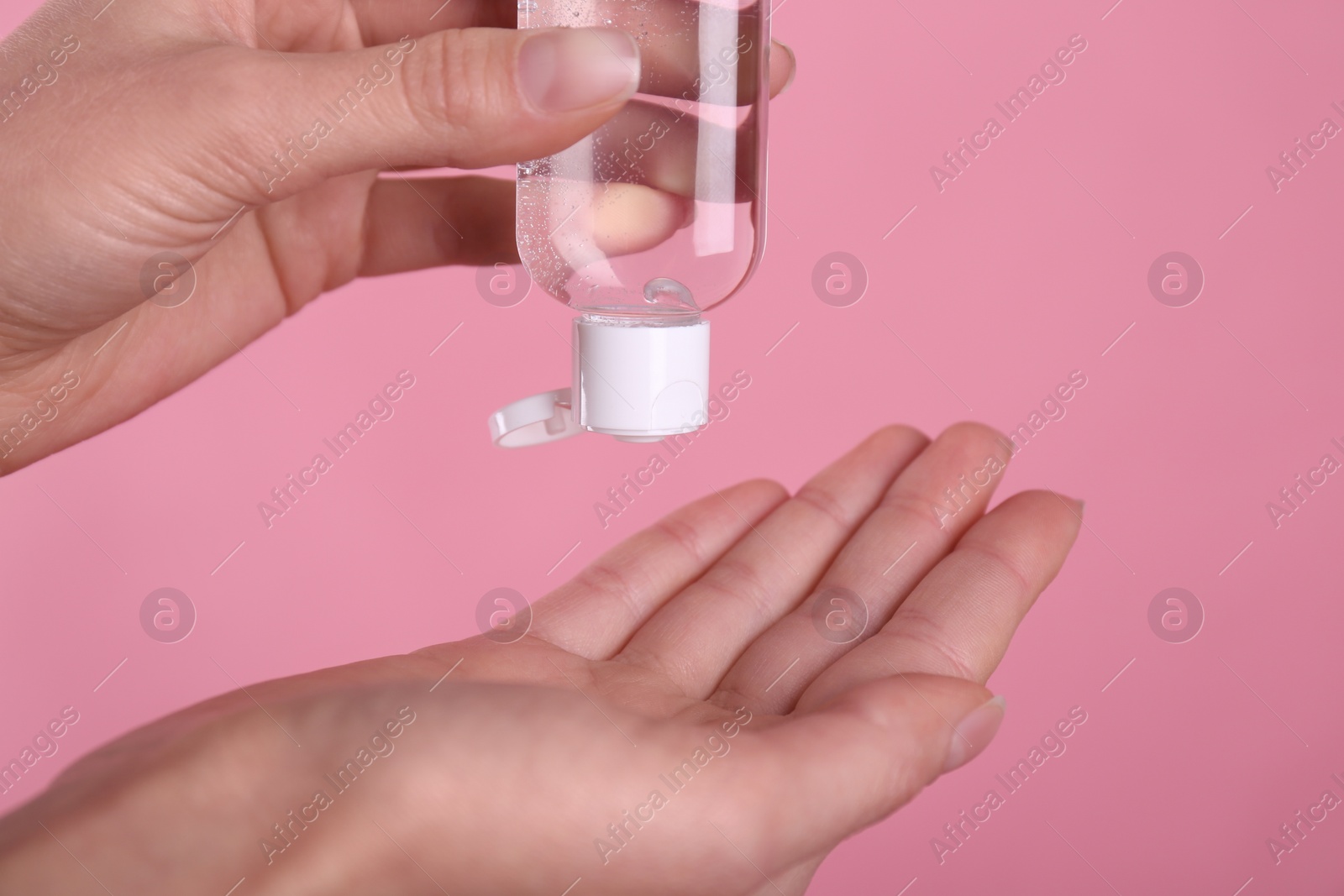 Photo of Woman applying antiseptic gel on pink background, closeup