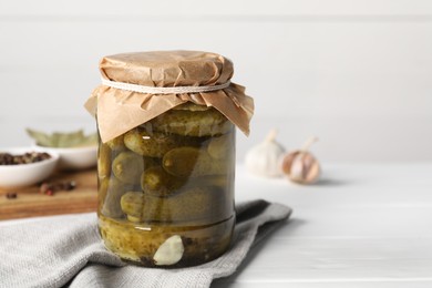 Photo of Tasty pickled cucumbers in jar and ingredients on white table. Space for text