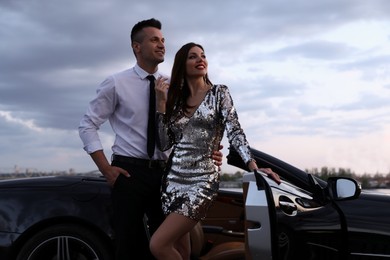 Photo of Beautiful couple near luxury convertible car outdoors