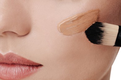 Photo of Woman applying foundation on face with brush, closeup