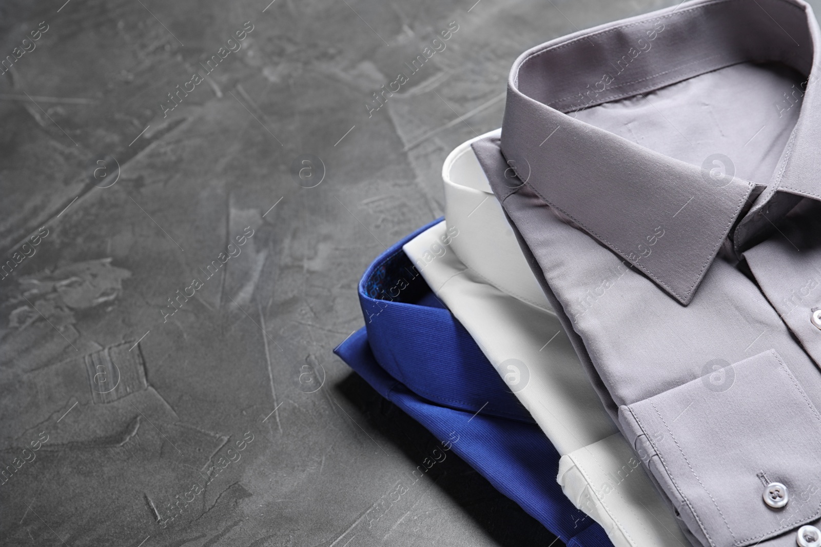 Photo of Stylish shirts on grey stone table, space for text. Dry-cleaning service