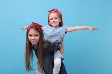 Cute little sisters on light blue background