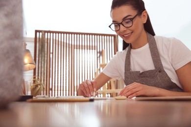 Photo of Young woman drawing with pencil at table indoors. Space for text