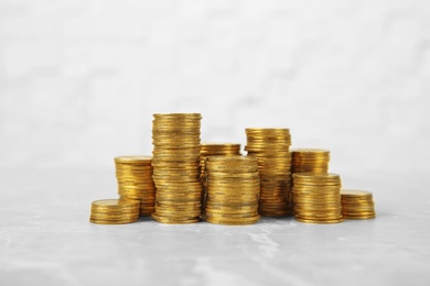 Photo of Many stacks of coins on table against light background