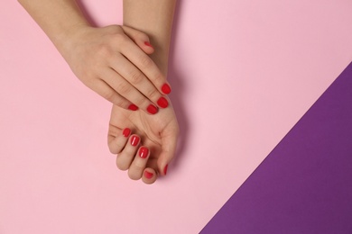 Photo of Woman showing red manicure on color background, top view with space for text. Nail polish trends