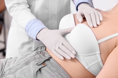 Mammologist checking woman's breast in hospital, closeup