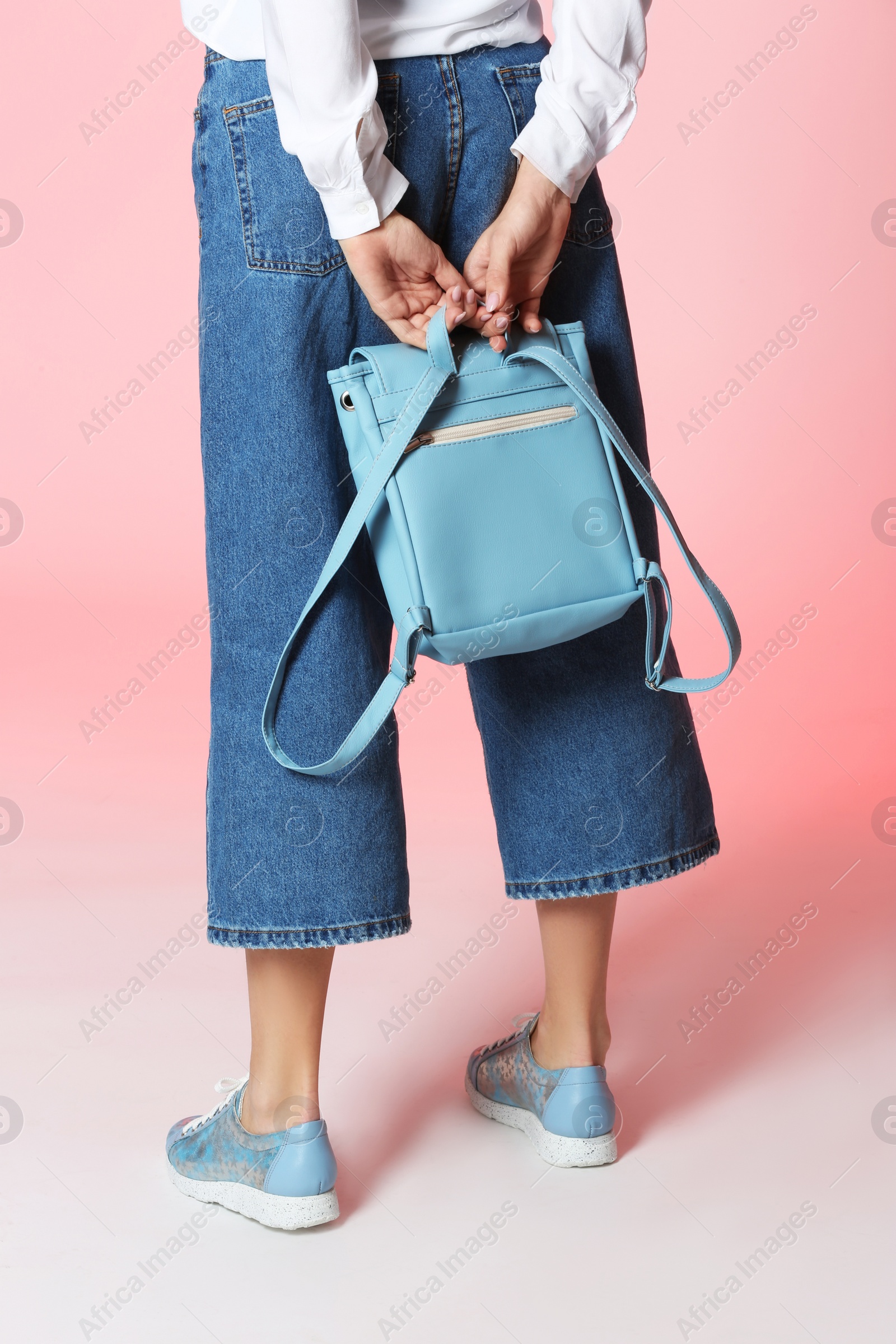 Photo of Woman in stylish shoes with backpack on color background