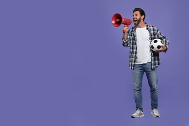 Photo of Emotional sports fan with soccer ball and megaphone on purple background, space for text