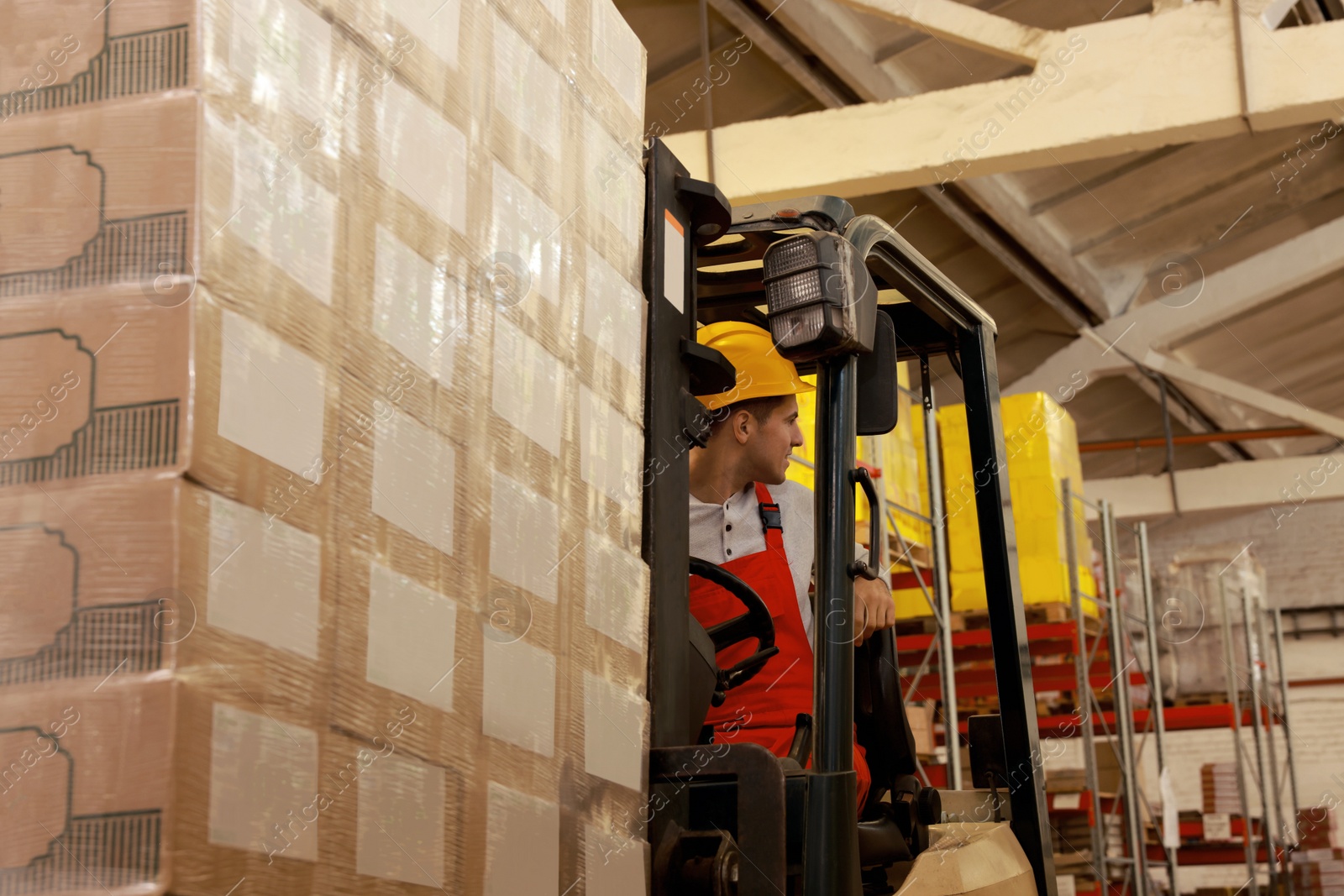 Image of Worker sorting cardboard boxes with forklift truck in warehouse. Logistics concept