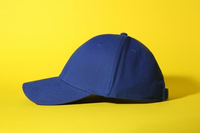 Stylish blue baseball cap on yellow background