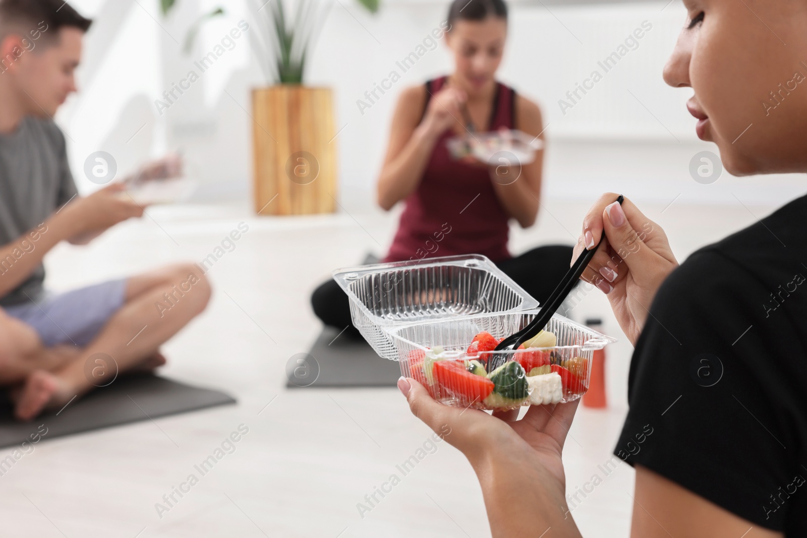 Photo of Group of people eating healthy food after yoga class indoors, closeup. Space for text