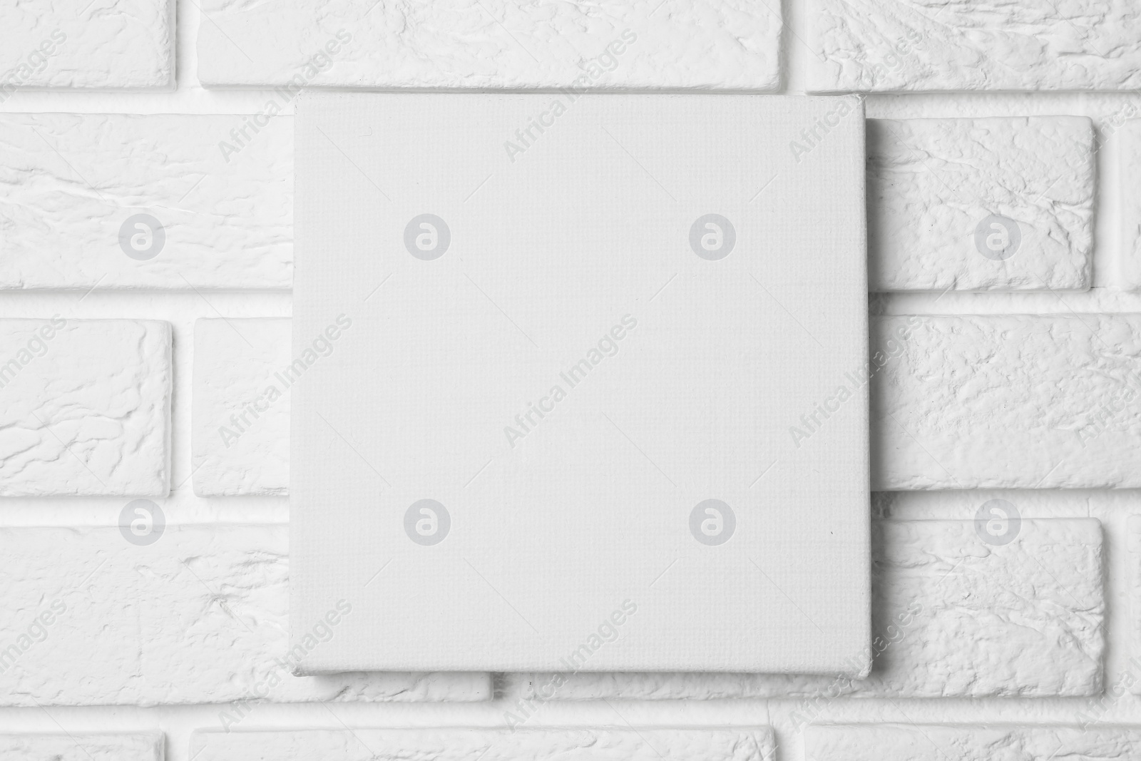 Photo of Blank canvas hanging on white brick wall, space for text
