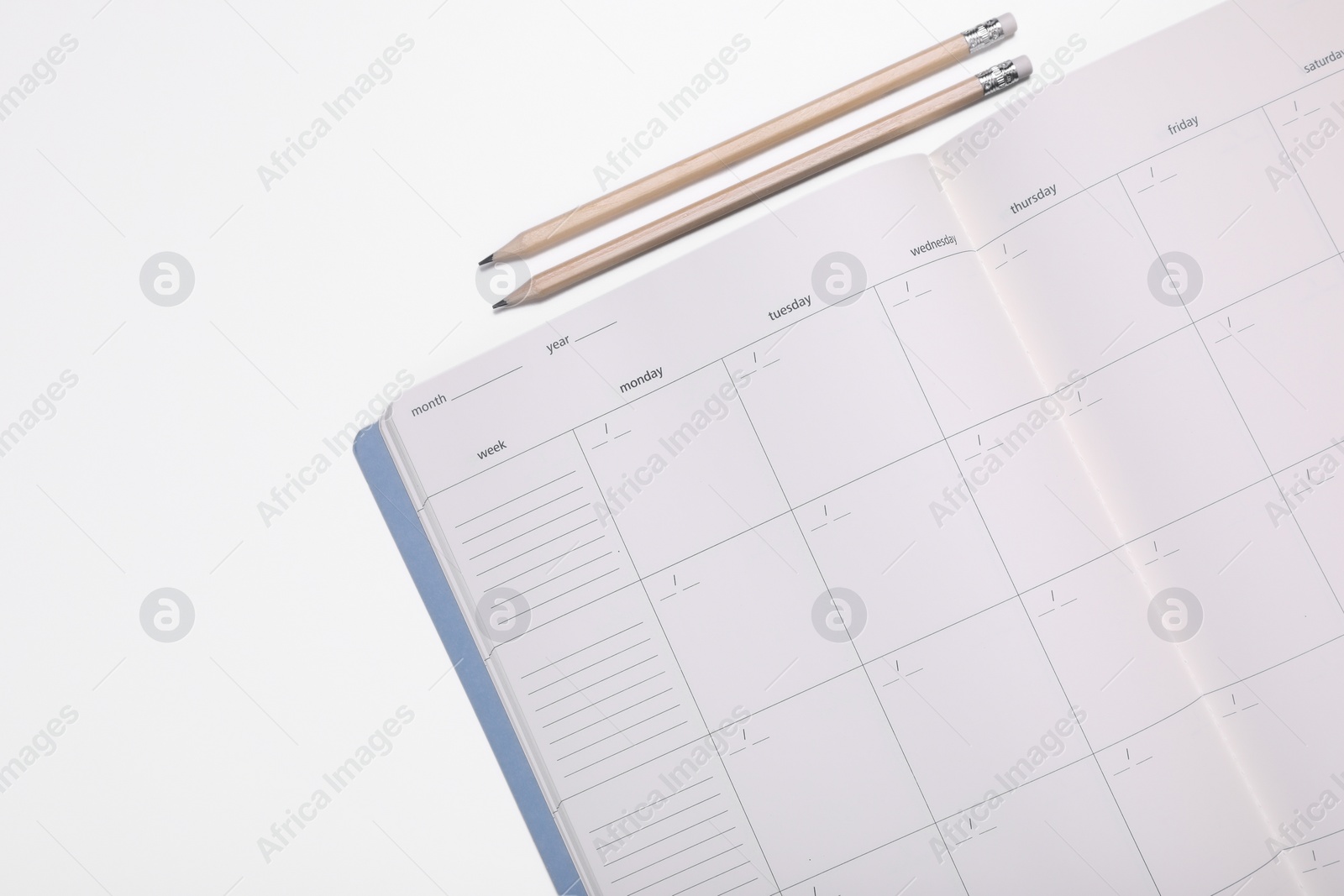 Photo of Open monthly planner and pencils on white background, top view. Space for text