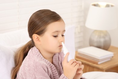 Little girl using nasal spray in bedroom