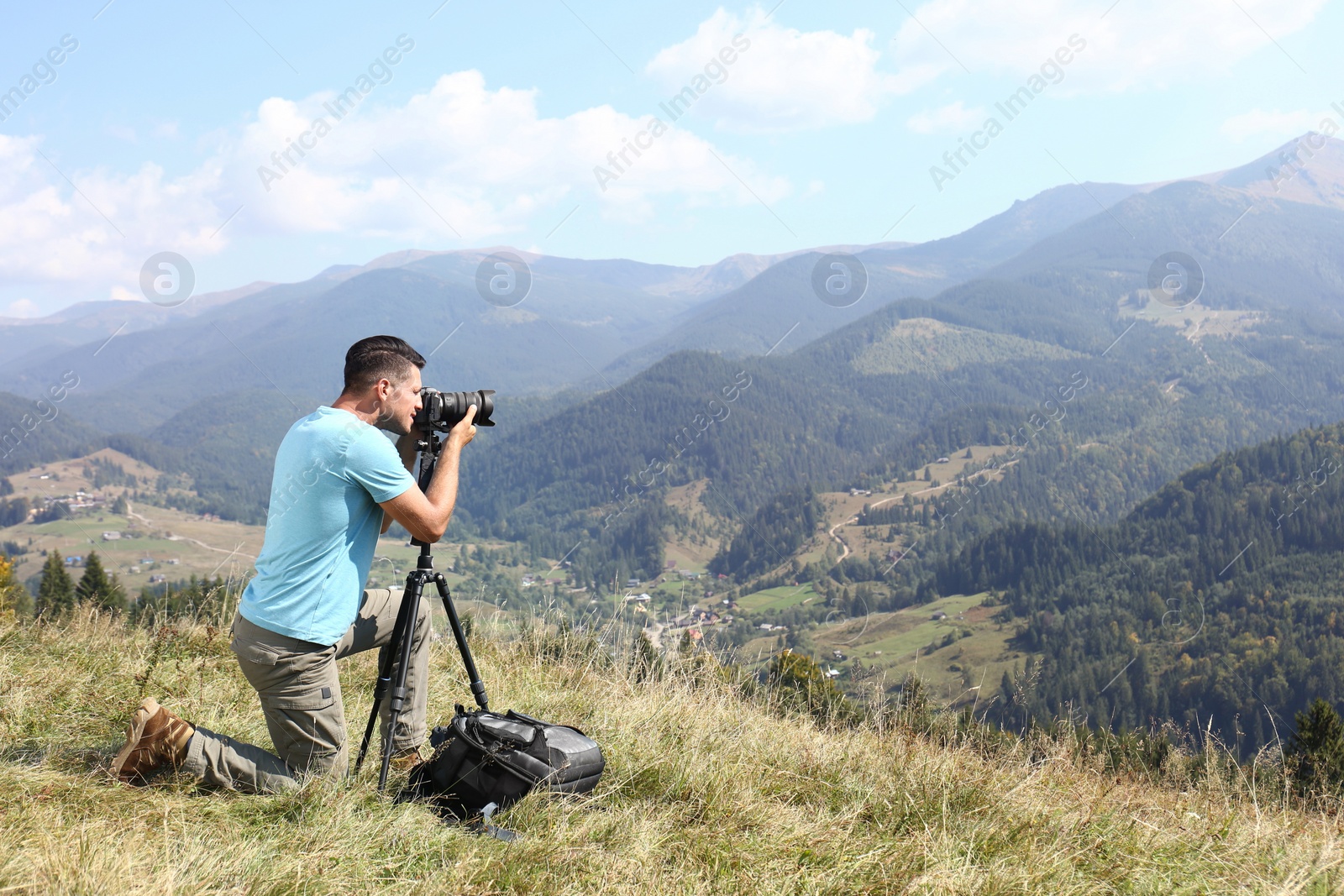 Photo of Man taking photo of mountain landscape with modern camera on tripod outdoors