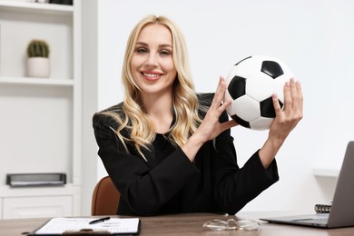 Photo of Happy woman with soccer ball at table in office