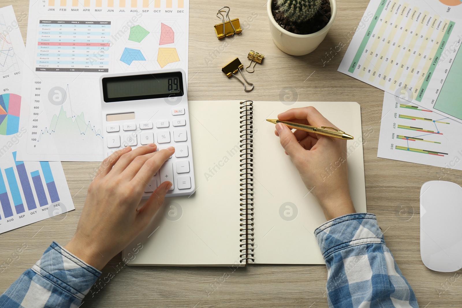 Photo of Accountant using calculator while taking notes at wooden table, top view