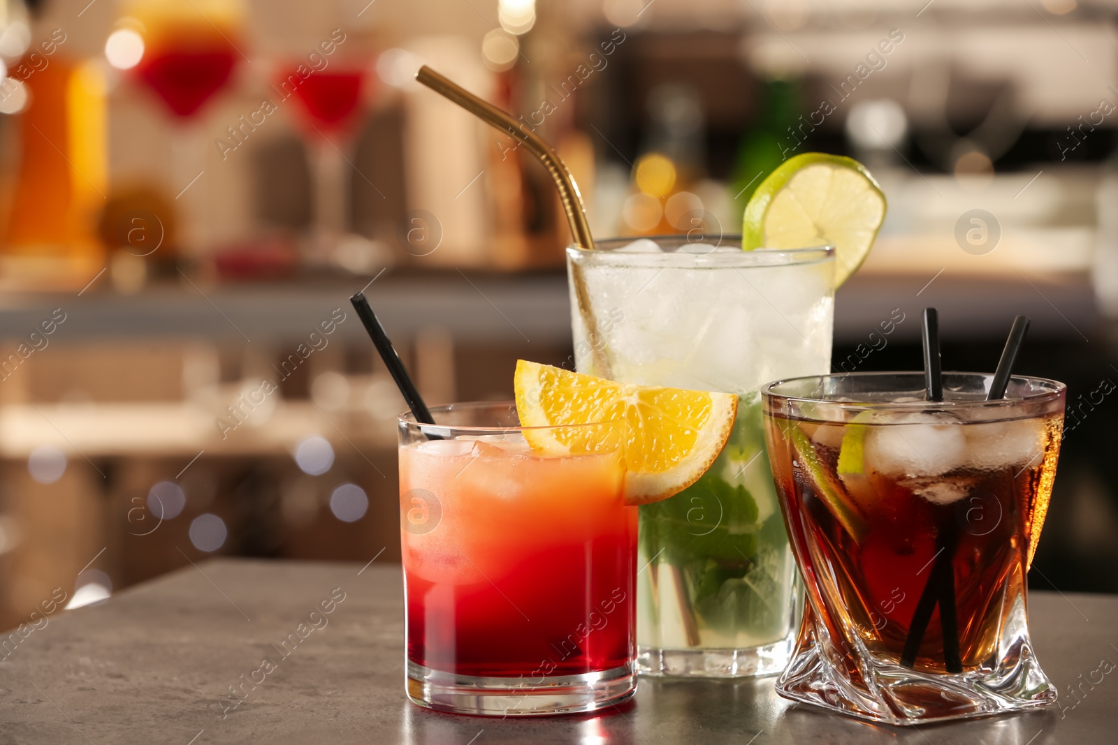 Photo of Different delicious cocktails on grey table in bar