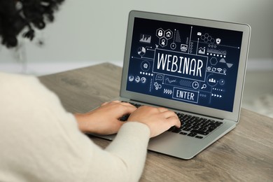 Online webinar, web page on computer screen. Woman using laptop at wooden table, closeup