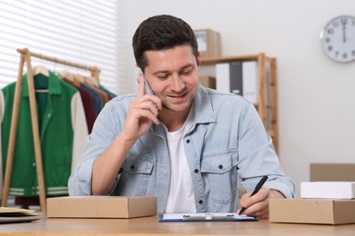 Photo of Seller talking on phone while working in office. Online store