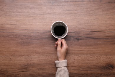 Photo of Woman with cup of coffee at wooden table, top view