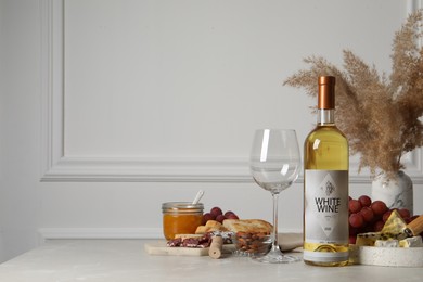Photo of Bottle of white wine, glass and snacks on table, space for text