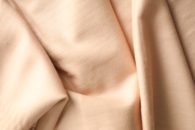 Photo of Beige soft cashmere scarf as background, closeup