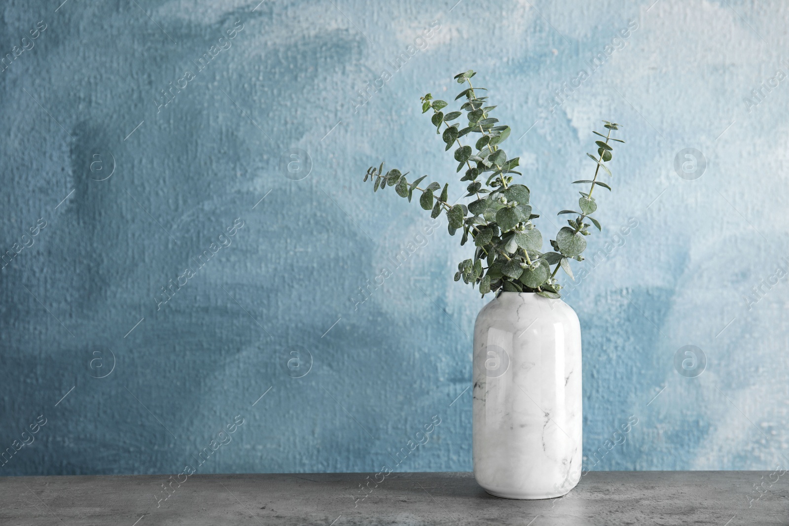 Photo of Bunch of eucalyptus branches with fresh leaves in vase on table