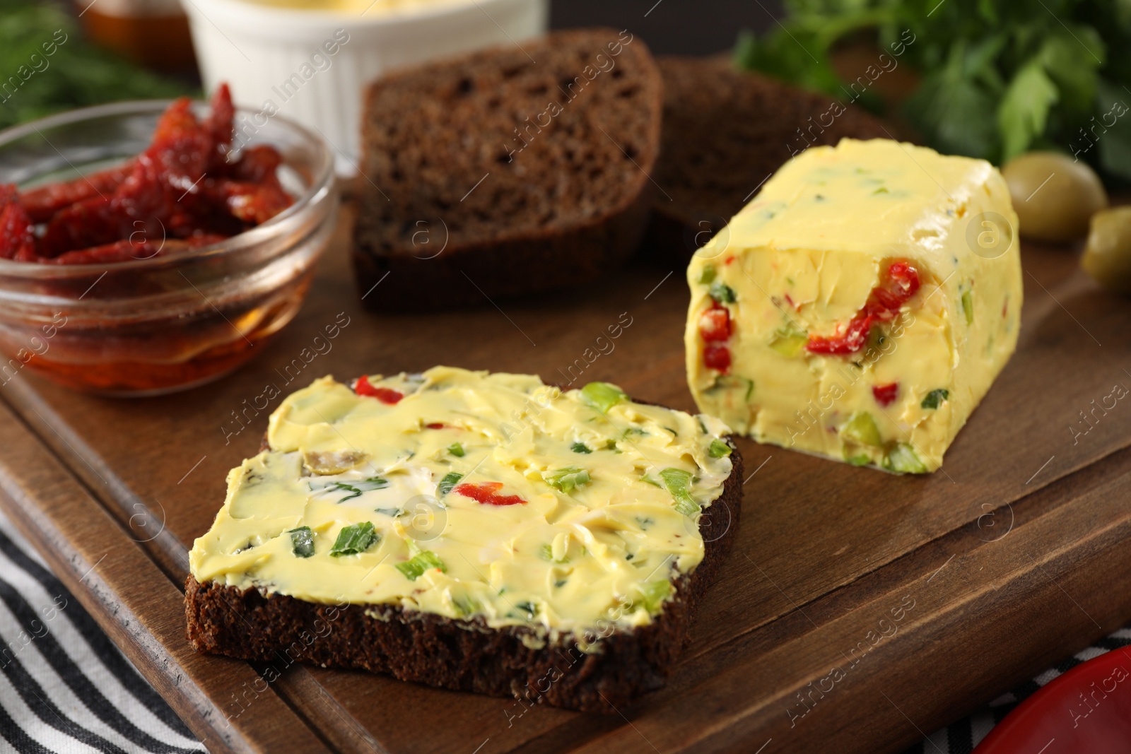 Photo of Tasty butter with green onion, chili pepper and rye bread on table, closeup