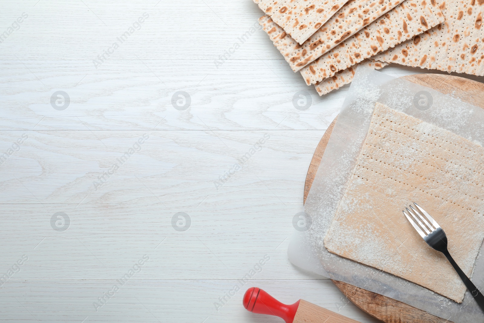 Photo of Matzos and raw dough on white wooden table, flat lay. Space for text