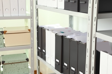 Folders and boxes with documents on shelves in archive