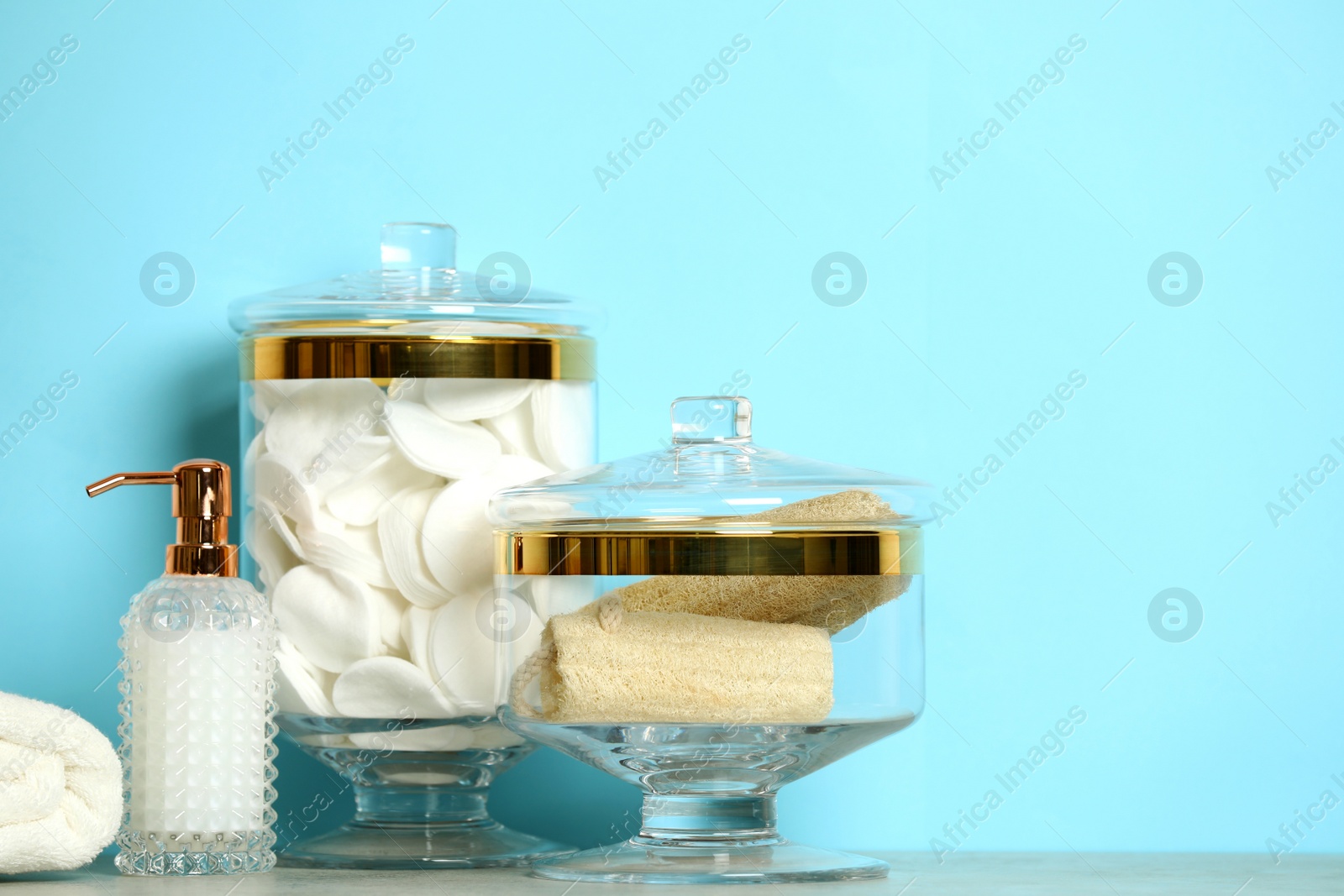 Photo of Composition of glass jar with cotton pads on table near blue wall. Space for text