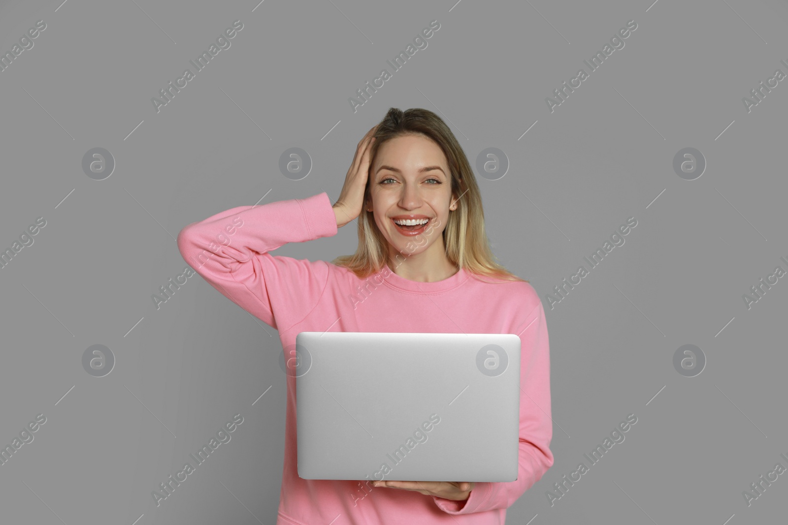 Photo of Young woman with modern laptop on grey background