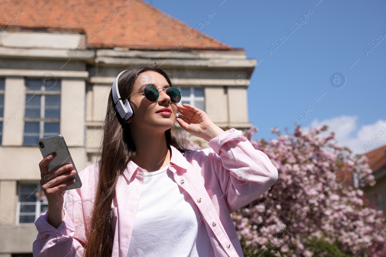 Photo of Young woman listening to audiobook in park