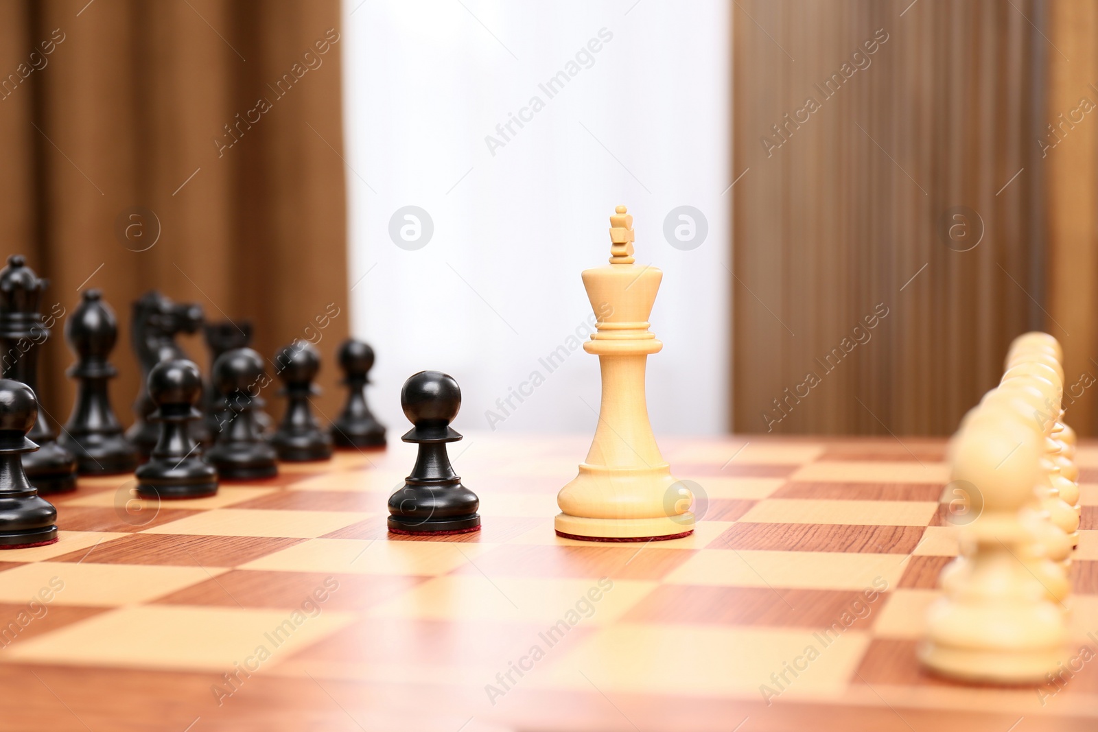 Photo of King and pawn pieces among others on chessboard indoors