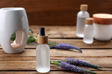 Lavender essential oil and flowers on wooden table, space for text