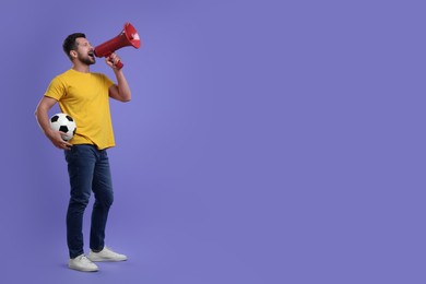 Photo of Emotional sports fan with ball and megaphone on purple background. Space for text