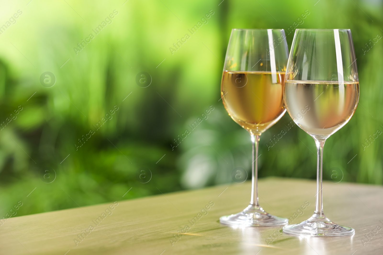 Photo of Tasty white wine in glasses on wooden table, space for text