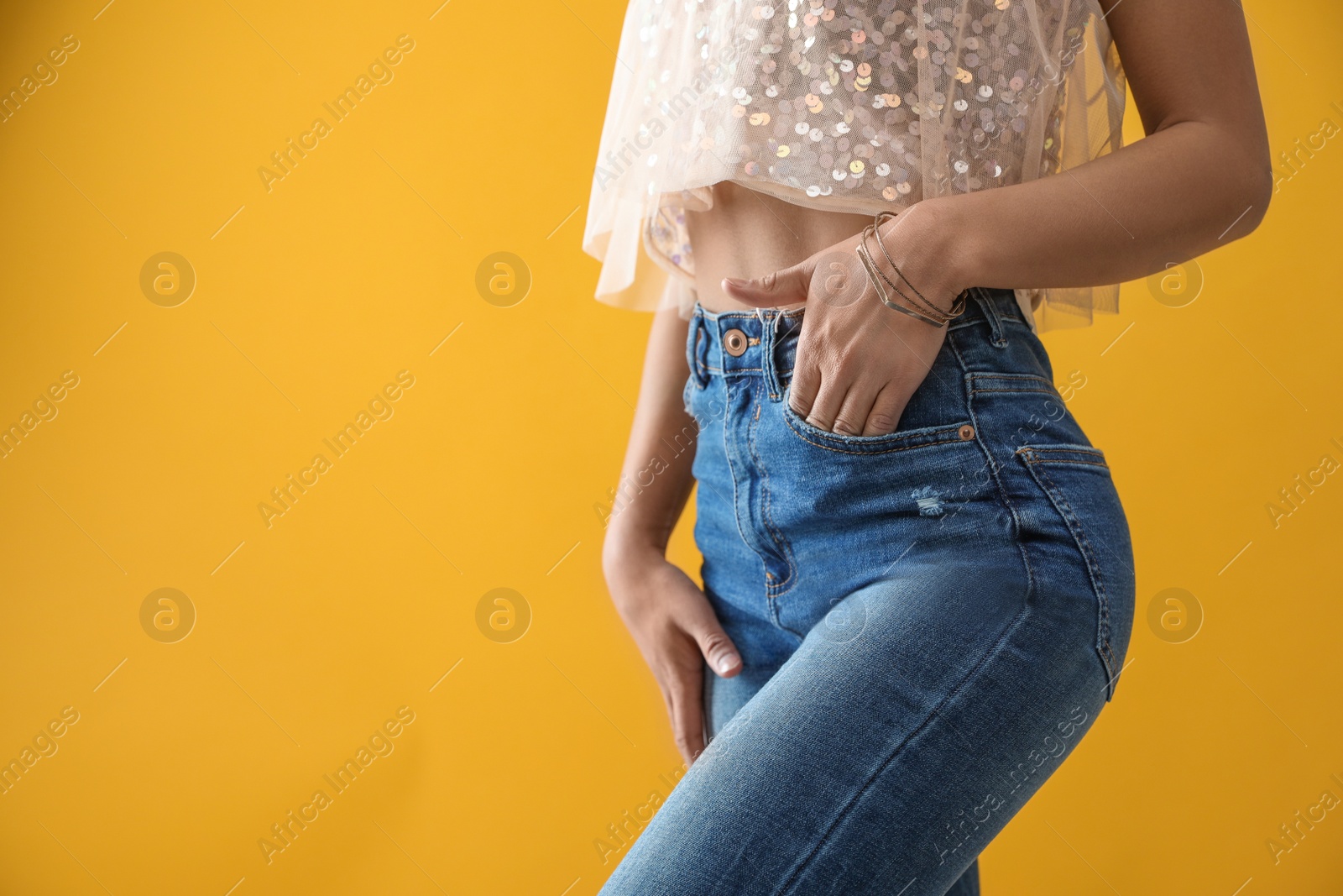 Photo of Woman wearing jeans on yellow background, closeup. Space for text