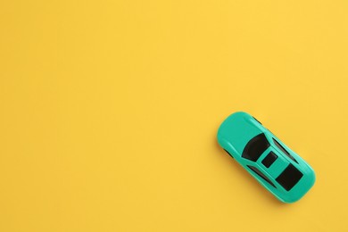 Photo of One turquoise car on yellow background, top view with space for text. Children`s toy
