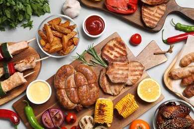 Photo of Flat lay composition with barbecued meat and vegetables on light table