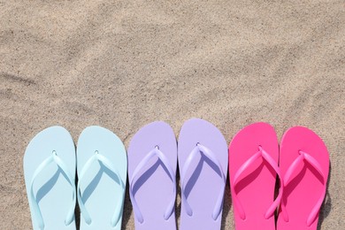 Stylish colorful flip flops on sand outdoors, flat lay. Space for text