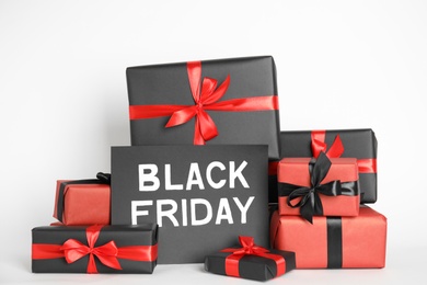 Photo of Many gift boxes and sheet of paper with words Black Friday on white background