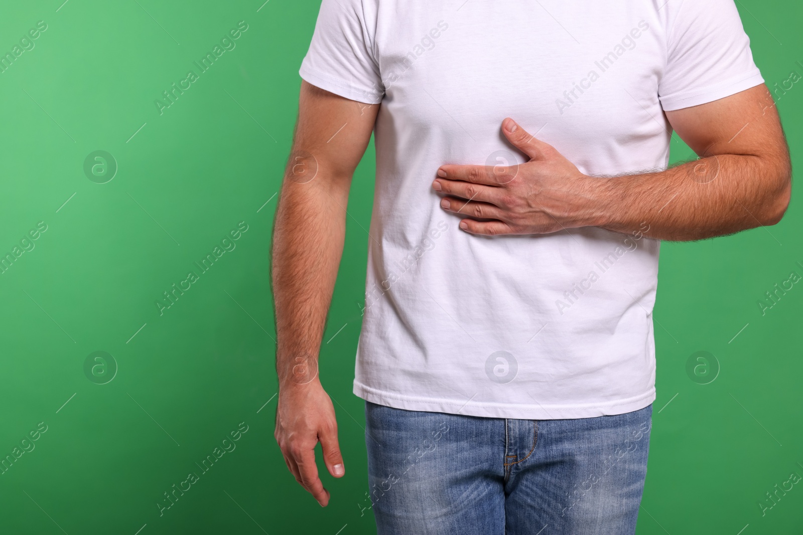 Photo of Man suffering from stomach pain on green background, closeup and space for text