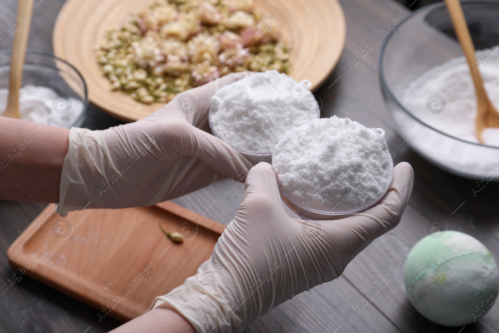 Photo of Woman in gloves making bath bomb at table, closeup