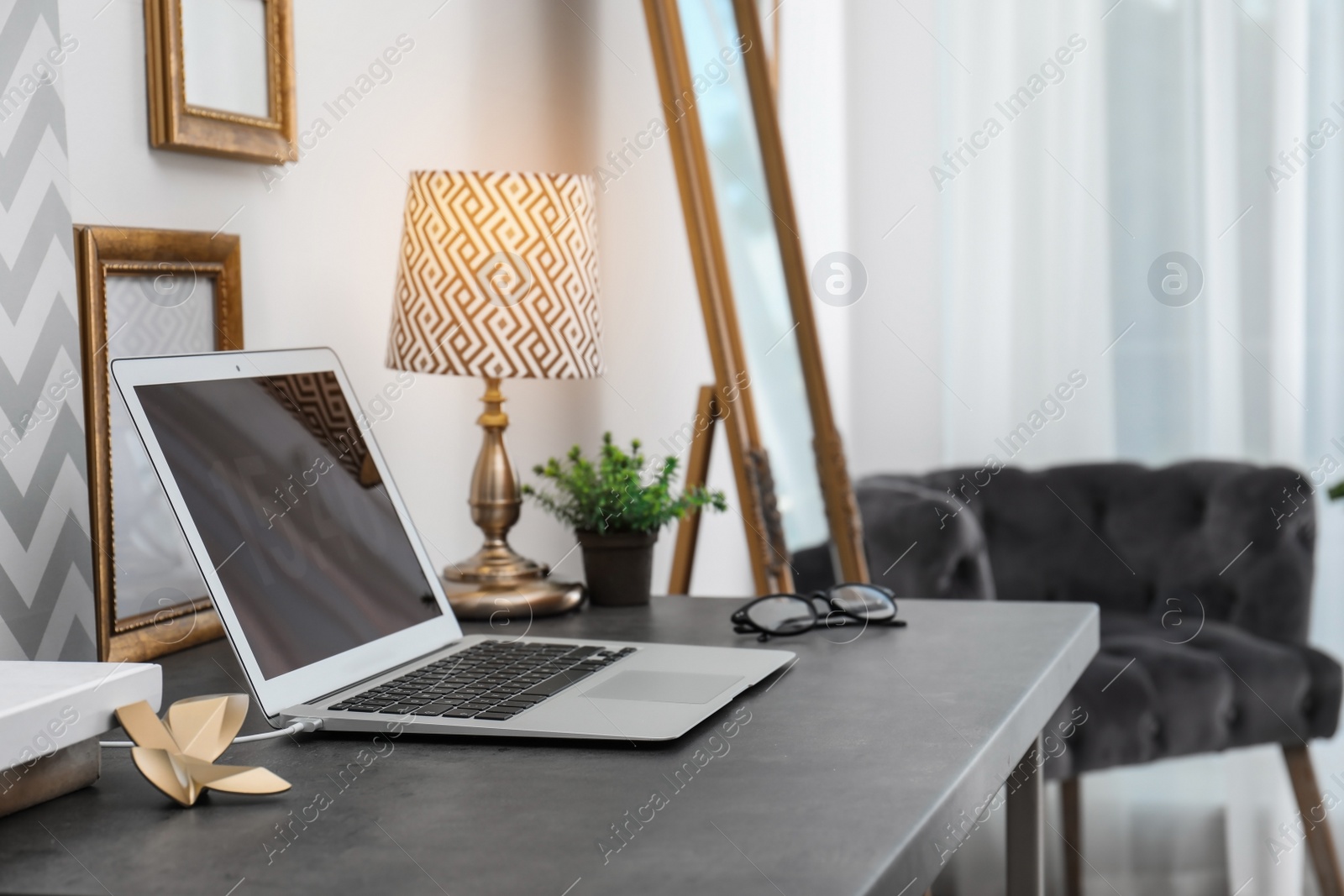 Photo of Stylish workplace with modern laptop on table indoors